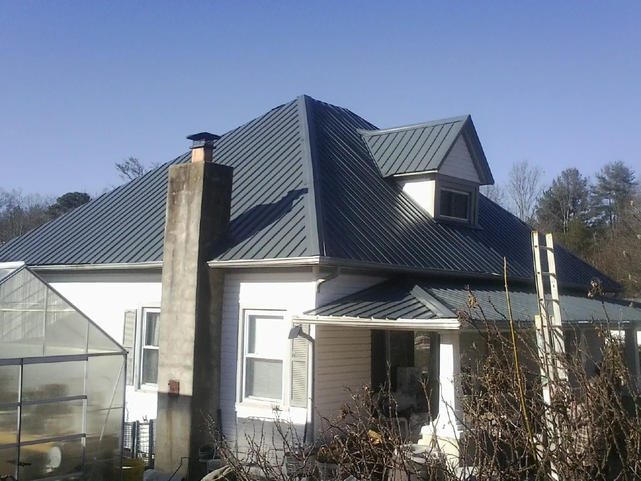 Dark blue standing seam metal roof on a white farmhouse with dormer — Slate & Tile Roof Repair by Roofing Brothers in Tully