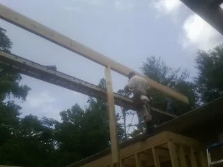 Carpenter setting a ridge beam over a new addition frame — Ice Dam Removal by Roofing Brothers in Tully