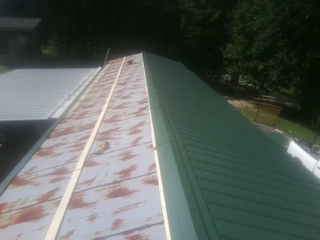 Old rusted panels beside newly installed green metal roofing — Wind Damage Roof Repair by Roofing Brothers in Tully