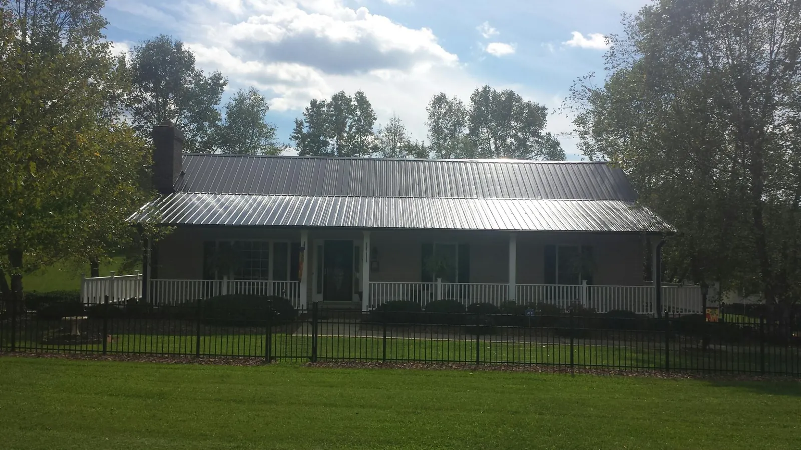 Gray metal roof on a brick ranch with a full width front porch — Gutter Guard Installation work by our crew in Tully